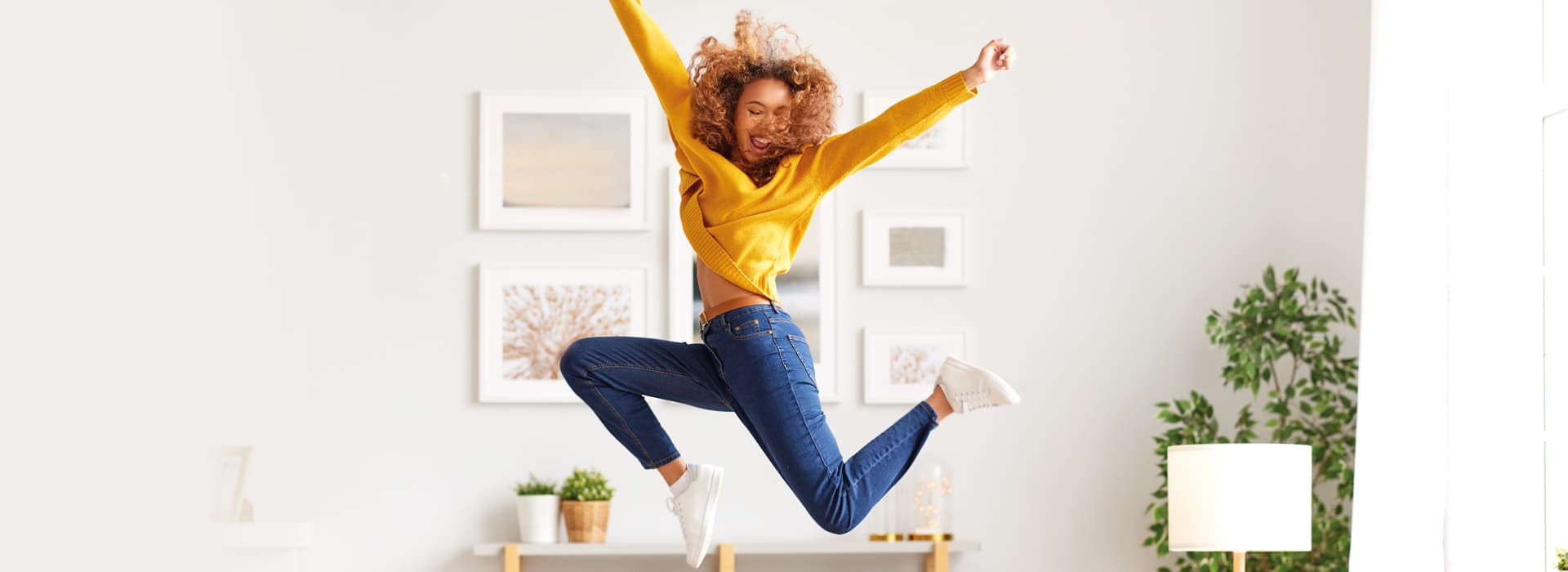 Froehliche Frau springt in hellem modernem Raum