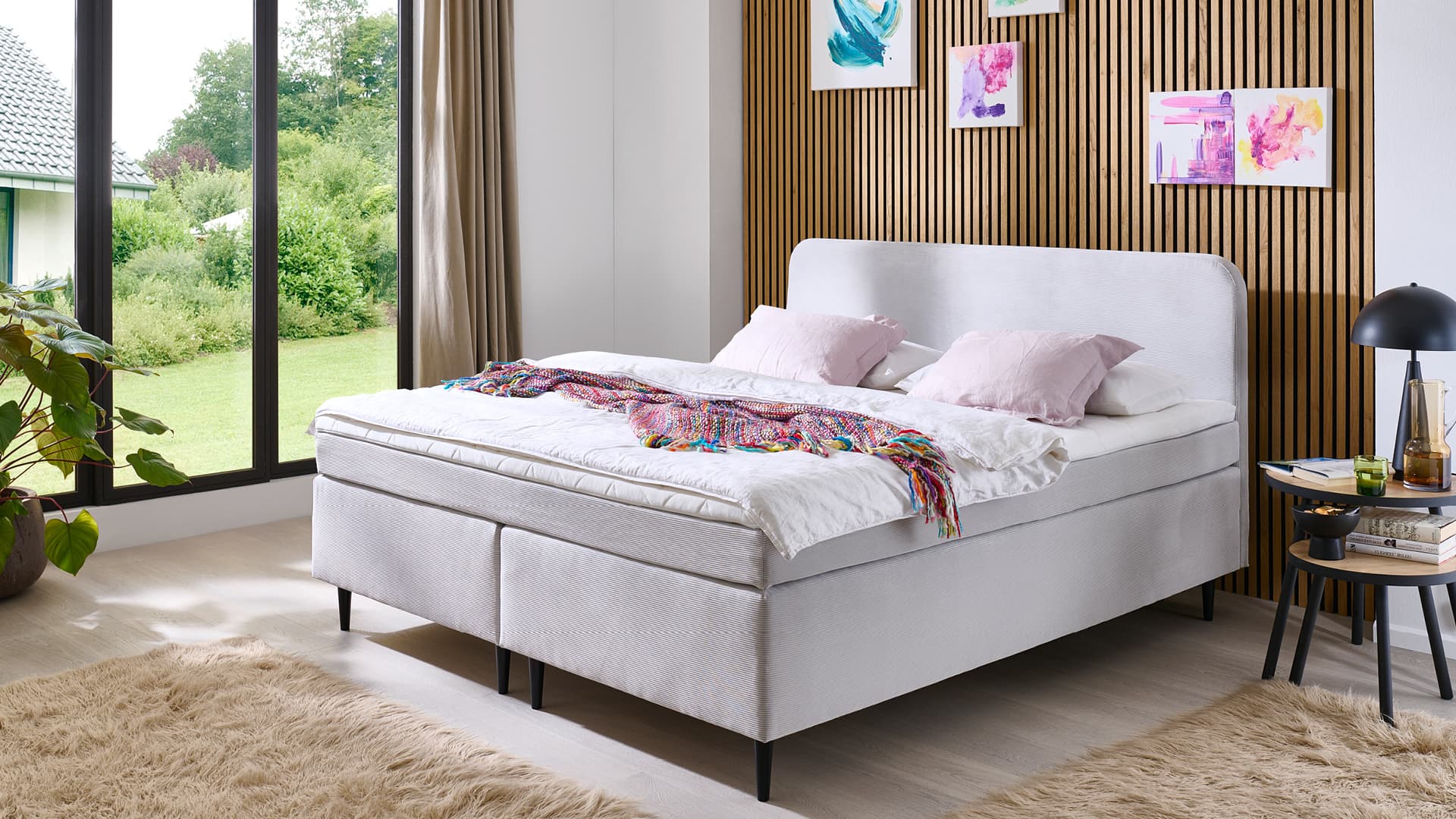 elegantes boxspringbett in hellem stoffbezug mit abgerundetem kopfteil