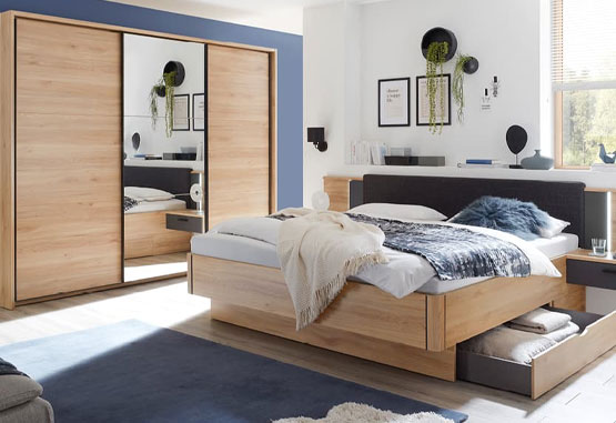 schlafzimmer in heller holzoptik mit spiegelschrank und stauraumbet